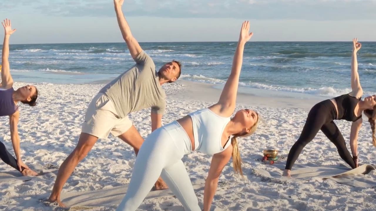 Group yoga class on the white sand beach